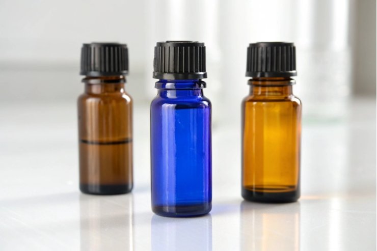 Colored dropper bottles Blue and amber essential oil dropper bottles with DIN18 caps on white surface