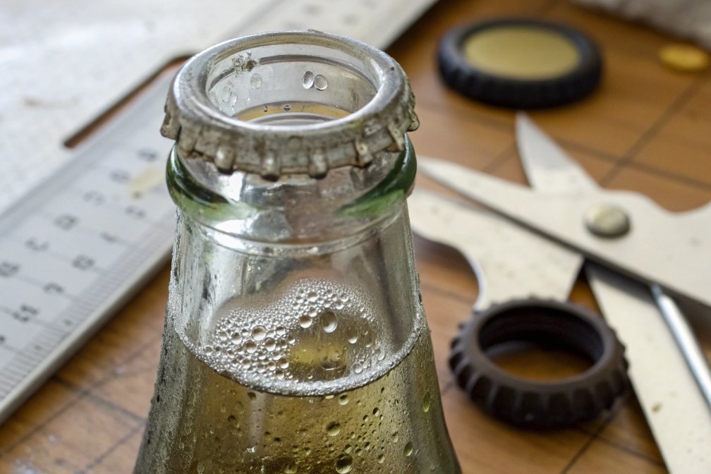 Close-up of a glass bottle showing carbonation bubbles and a metal bottle cap