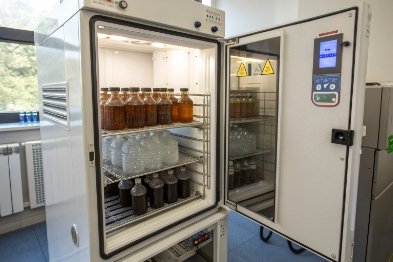 Photostability chamber with bottled samples stored on racks for controlled light exposure testing