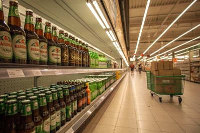 Beer bottles displayed on supermarket shelf aisle, showcasing retail glass packaging options