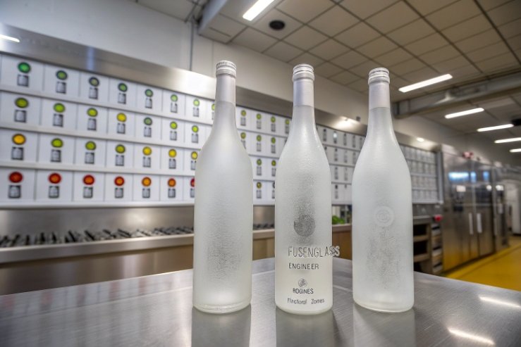 Frosted glass wine bottles displayed on stainless table in quality control room