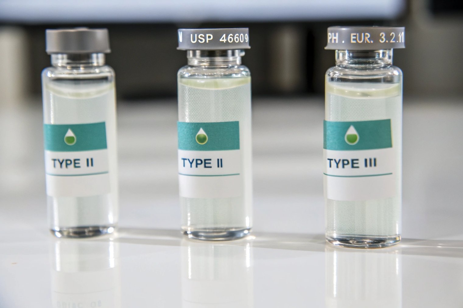 Type II and Type III clear pharmaceutical glass vials with aluminum closures on bench