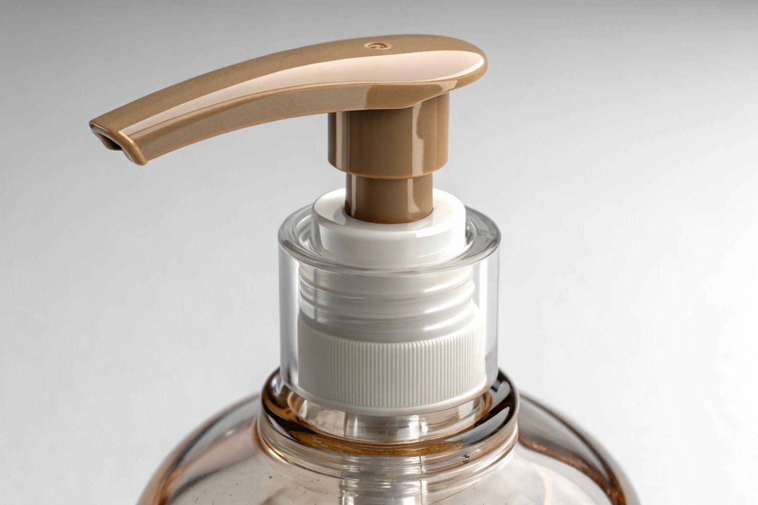 gold plastic lotion pump on clear cosmetic bottle close up