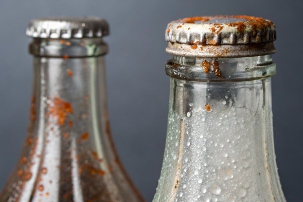 Rusty metal caps on glass bottles showing closure corrosion and sealing quality issues
