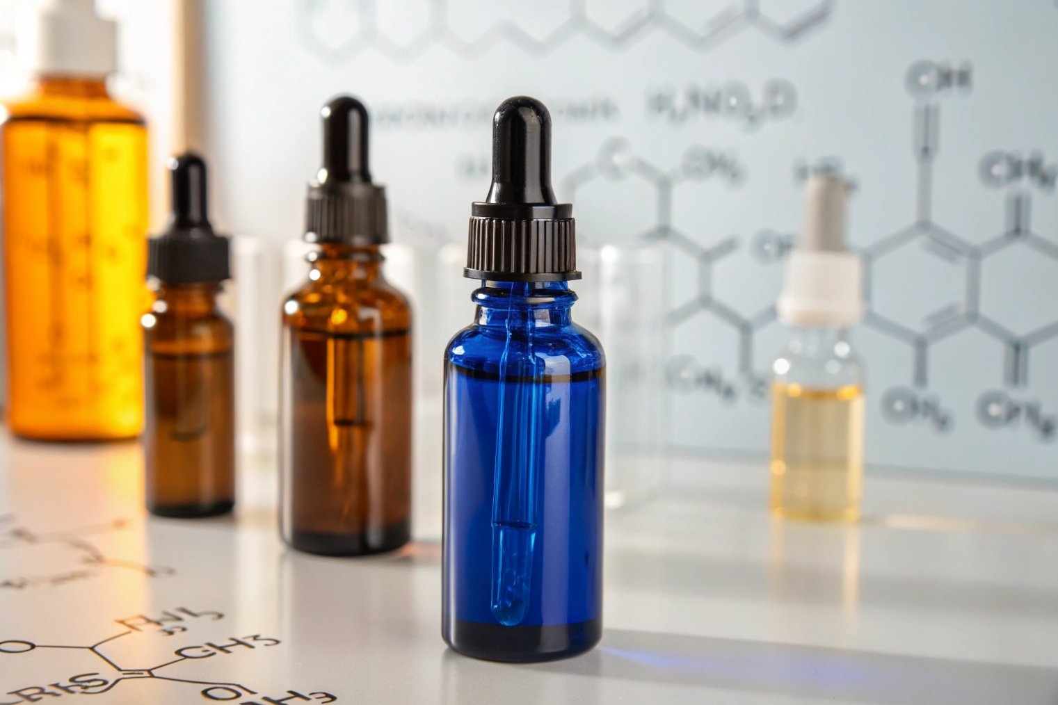 blue glass dropper bottle with amber bottles in laboratory chemical formula background