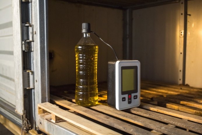 Plastic bottle with liquid beside temperature logger inside cargo container for transport testing