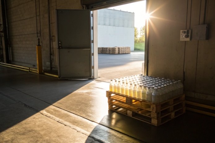 Pallet of filled glass bottles staged at loading dock with sunlight for dispatch