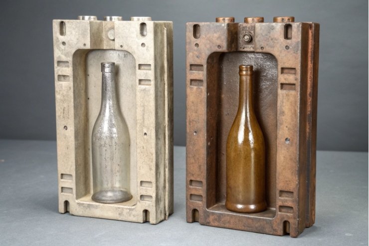 Two glass bottle molds displaying clear and amber bottle forming cavities