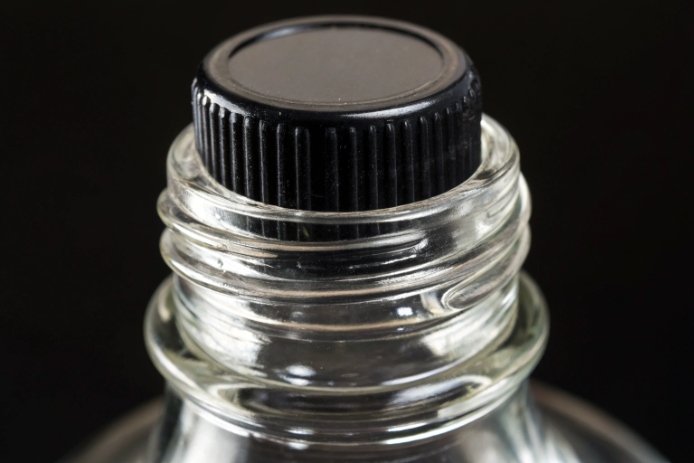 Close-up of plastic screw cap and threaded glass bottle neck