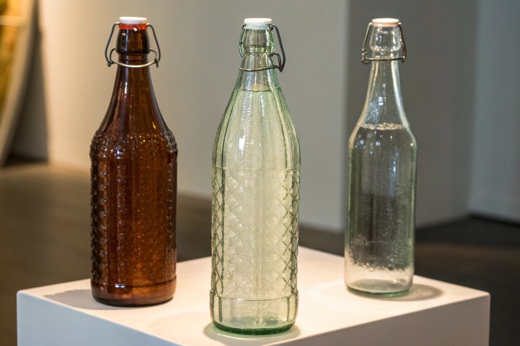 Three glass bottles with metal caps, different colors