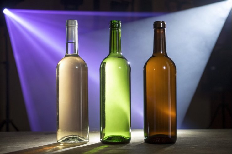 Clear green and amber empty wine bottles under dramatic lighting