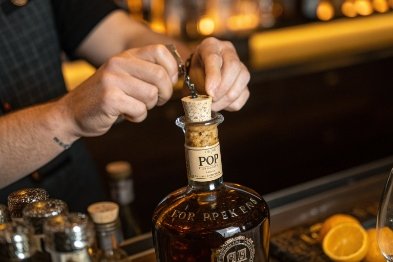 Bartender secures cork closure on premium whiskey bottle over bar counter