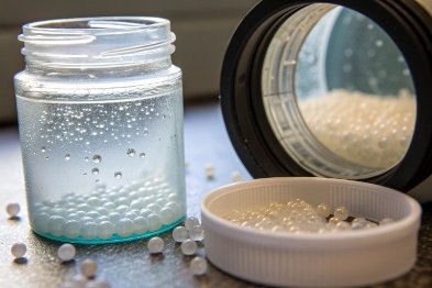 Open glass jar with clear gel beads beside lid, highlighting storage and spill control