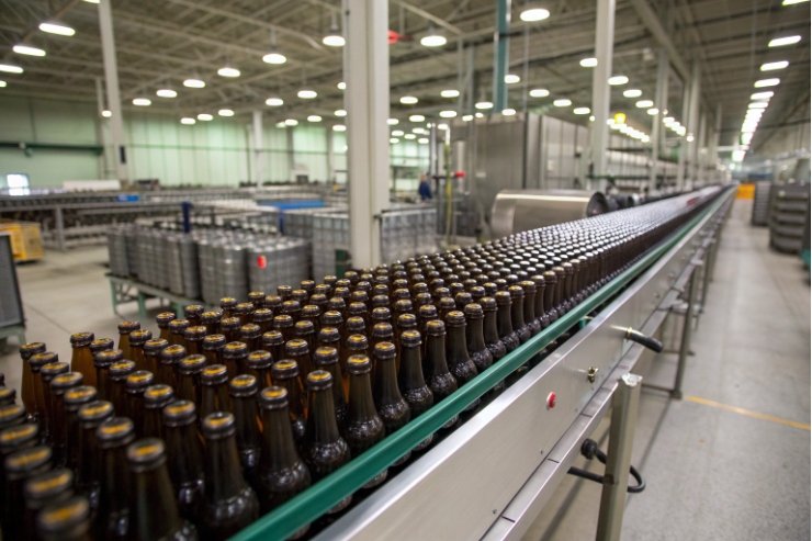 Amber beer bottles lined on conveyor in large-scale bottling plant
