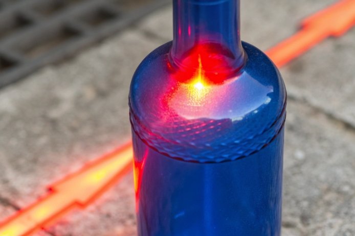 Close-up of blue glass bottle shoulder with heat spot glow showing stress concentration