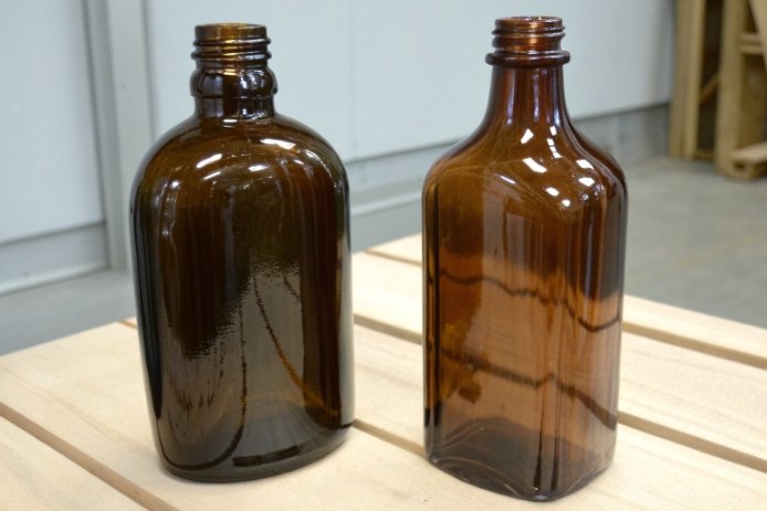 Two amber glass bottles compared for shape and finish in packaging quality check