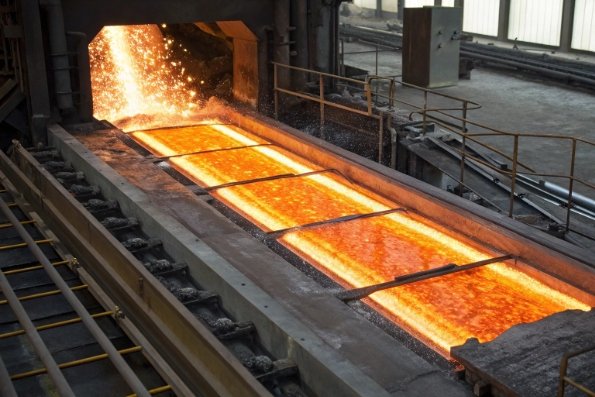 Molten glass bath in industrial furnace channel with sparks and intense heat