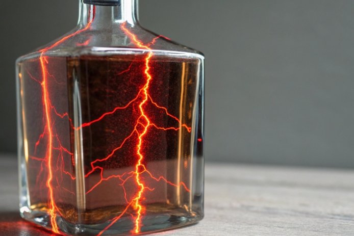 Clear glass liquor decanter with dramatic lightning reflection highlighting premium spirits bottle design