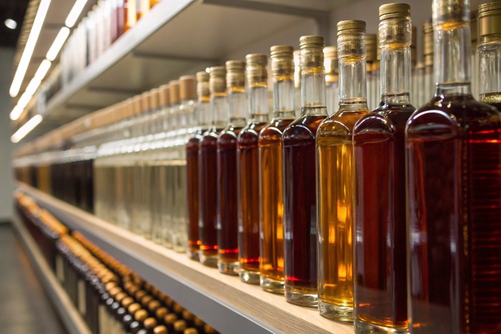 Backlit glass spirit bottles arranged on retail shelf showcasing rich amber and clear liquids