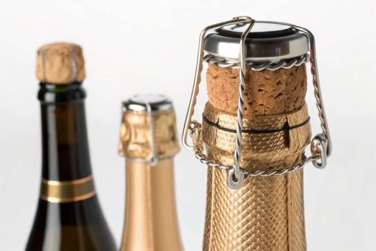 Close-up of champagne cork and wire cage closure on sparkling wine bottle neck.