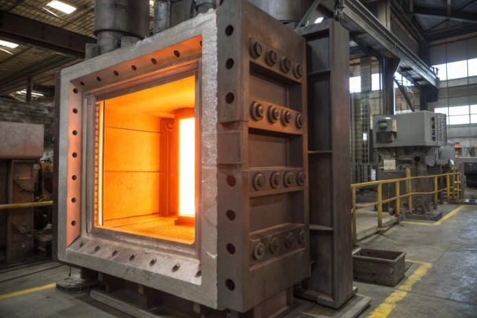 Industrial annealing lehr furnace chamber glowing hot for glass bottle heat treatment.