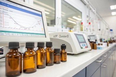 Amber sample bottles lined in lab beside spectrophotometer and screen chart results
