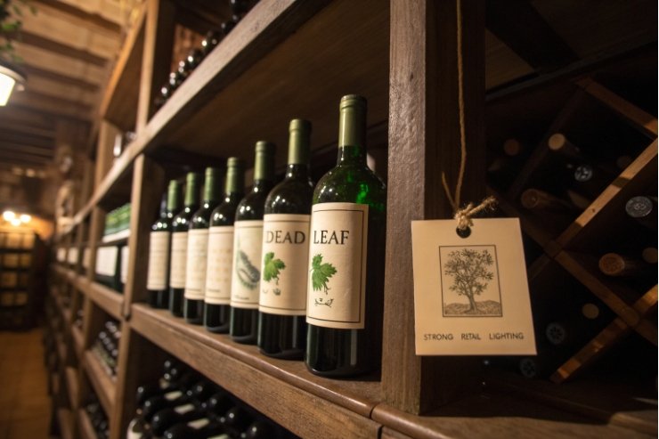 Green glass wine bottles lined on wooden cellar racks with hanging label tag