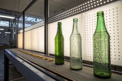 Green glass bottles on conveyor under inspection lights for defect detection