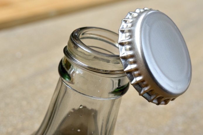Loose crown cap on glass bottle mouth showing improper seal and closure fit issue