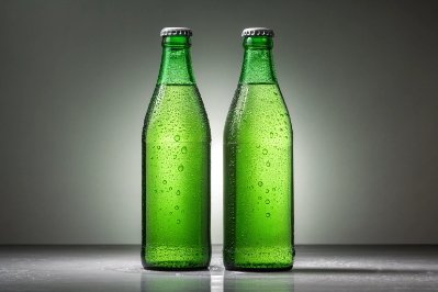 Two green glass beer bottles with condensation isolated on studio background