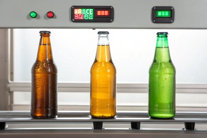 Amber, flint, and green beer bottles on conveyor under inline color inspection.