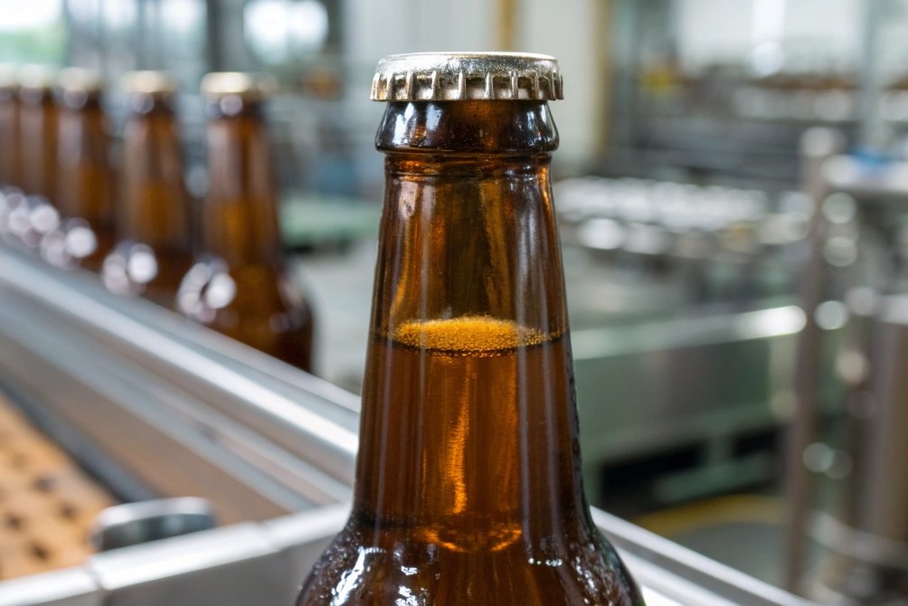 Close-up of a bottle with a metal cap in a production line