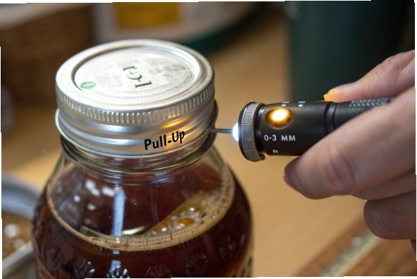Pull up vacuum seal test on jar lid using micrometer probe tool