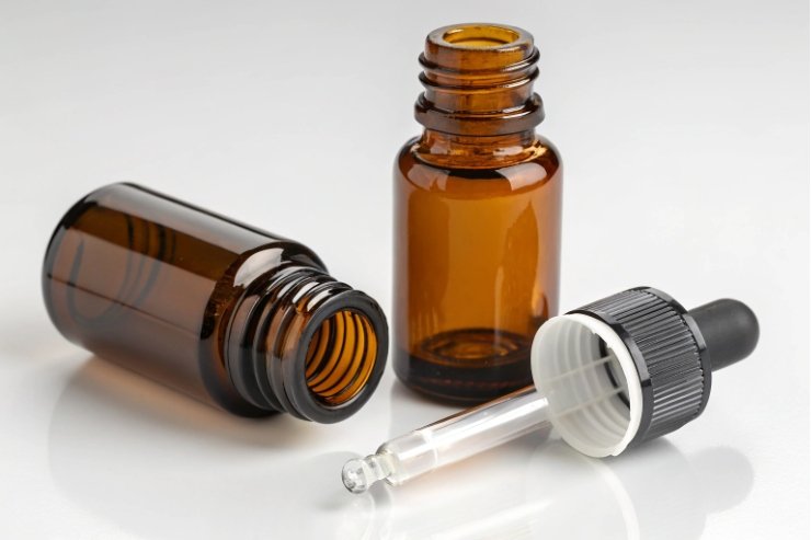 Amber bottle pipette Open amber essential oil bottle with separate glass pipette dropper on white background