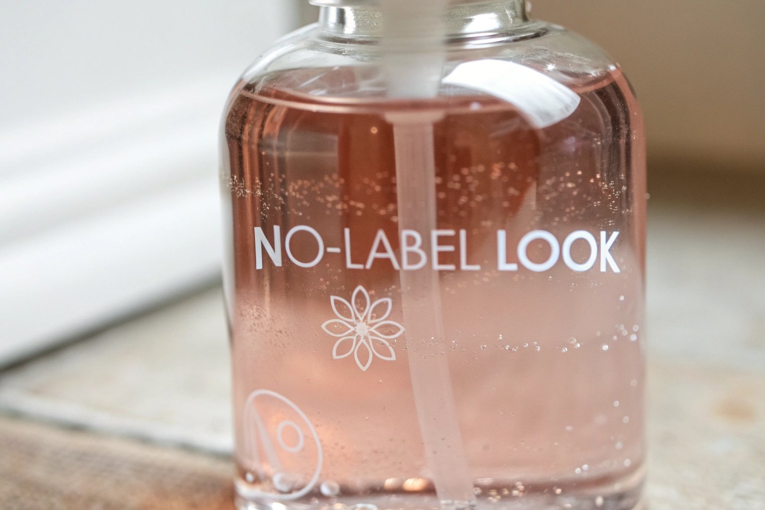clear glass soap bottle with pink formula and no label look decoration