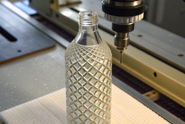 Embossing Precision Test Embossed glass bottle under precision drilling machine for decoration and quality testing