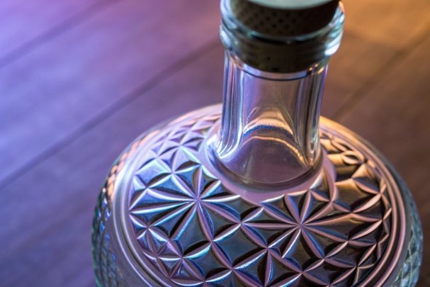 Close-up of patterned glass bottle shoulder showing geometric embossing and premium finish