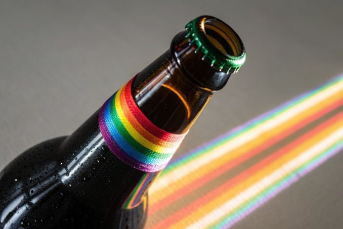 Brown glass bottle with rainbow label and prism light streak showing decorative packaging effect