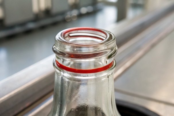 Close-up of glass bottle neck with red sealing ring for closure fit check