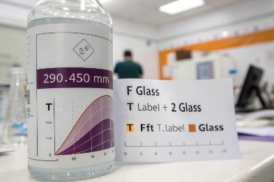 Glass bottle labeled 290-450 nm with UV curve chart for light transmission testing