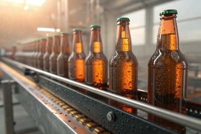 Amber glass beer bottles on conveyor with condensation during cooling and processing