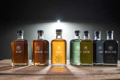 Spirits bottle lineup showing flint, smoked, amber, and green glass for light protection