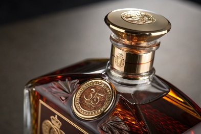 Luxury whiskey decanter close-up with gold stopper and medallion over amber spirit