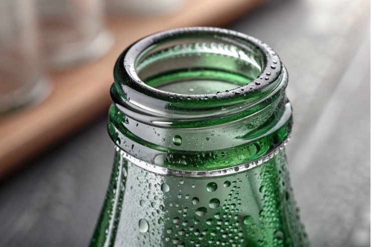 Macro view of green glass bottle neck finish with water droplets