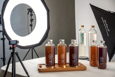 Studio product shoot setup with multiple glass beverage bottles, lights, and backdrop