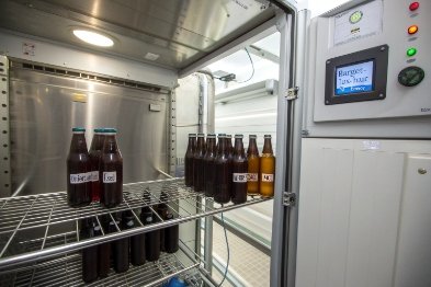 Beverage bottles in UV test cabinet for light stability and color protection evaluation