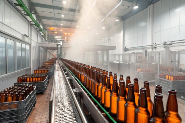 Amber glass bottles on conveyor in bottling plant during steam washing sterilization