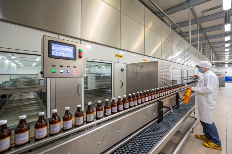 Cleanroom operator checking amber bottles on automated filling line
