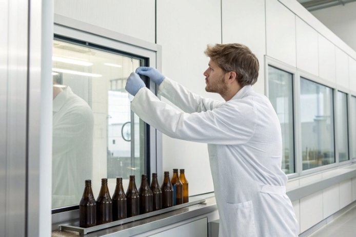 Quality inspector examining amber glass bottles in laboratory inspection room