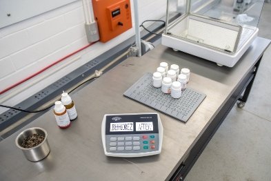 Laboratory scale and small medicine bottles on stainless bench for pharmaceutical packaging testing